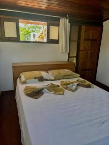 a bed with white sheets and pillows and a window at Apto pé na areia de Gamboa do Morro in Cairu