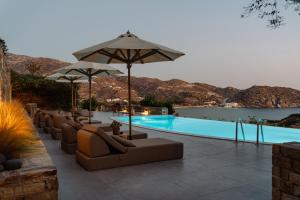 a swimming pool with couches and umbrellas next to a pool at Gianemma Luxury Apartments in Mylopotas