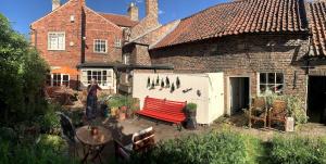 una donna in piedi davanti a una casa con una panchina rossa di Crofton Dye House a Yarm