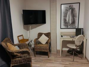 a living room with chairs and a desk and a tv at Pension Osthoff in Wülfrath