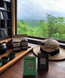 une table avec chapeaux, livres et fenêtre dans l'établissement Taba tea house & tea garden, à Ozurgetʼi
