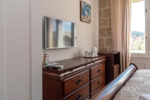 a bedroom with a dresser and a television on a wall at Queen Teuta Luxury Rooms Split in Split