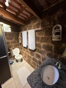 a stone bathroom with a sink and a toilet at Recanto Toca do Rato in Jaciara