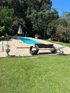 a swimming pool with a bench in the grass at Recanto Toca do Rato in Jaciara