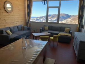 a living room with couches and a large window at appartement 8 couchages au lioran rando vtt ski in Le Lioran