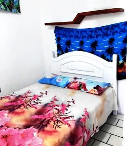 a bedroom with a white bed with pink flowers at pousada mar azul in Salvador