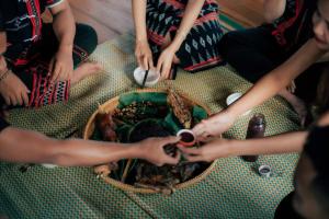 a group of people sitting around a table eating food at HomeStay Tre Vàng in A Xiêm