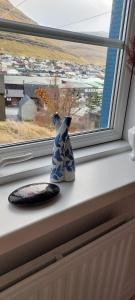 a blue and white vase sitting on a window sill at Cozy apartment in Klaksvík
