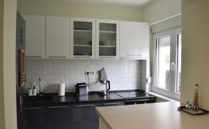 a kitchen with white cabinets and a black counter top at AeroVista Apartment in Surčin