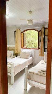 deux lits dans une chambre avec une fenêtre dans l'établissement Casa na Vila do Abraão - Ilha Grande, à Angra dos Reis