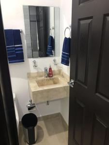 y baño con lavabo, espejo y toallas azules. en Departamento en Mazatlán, en Mazatlán