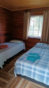 two beds in a wooden room with a window at Pousada Raio de Sol - SUPERAGUI - PR in Superagui