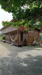 a wooden house with a hammock in front of it at Pousada Raio de Sol - SUPERAGUI - PR in Superagui