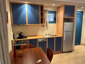 una cucina con armadi blu, tavolo e frigorifero di VERDE BLUE 313 Barbati a Barbati