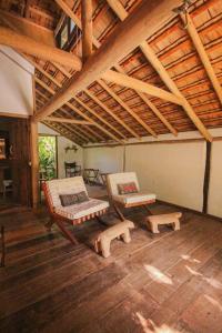 a living room with two chairs and a wooden ceiling at Pousada Quinta de Caraíva in Porto Seguro