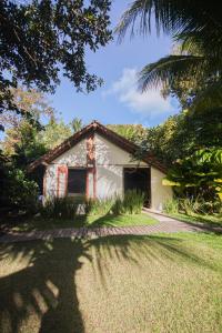a white house with a palm tree in front of it at Pousada Quinta de Caraíva in Porto Seguro