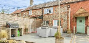 a brick house with a grill in a courtyard at April Cottage in Bacton