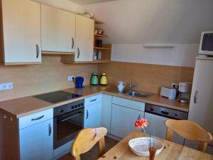 una cucina con mobili bianchi e un tavolo di legno di Geräumige 3-Zimmer Wohnung in ruhiger Lage a Wyk auf Föhr