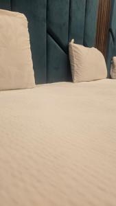 a bed with white sheets and pillows next to a wall at Hotel Family Guest House in Karachi
