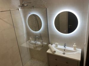 a bathroom with a sink and a shower with two mirrors at Chalet muguet & Jaccuzi privatif in Rochesson