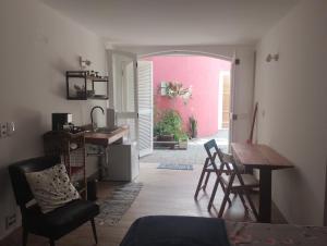 a room with a table and chairs and a pink wall at Estudio do Alto 2 in Sao Paulo