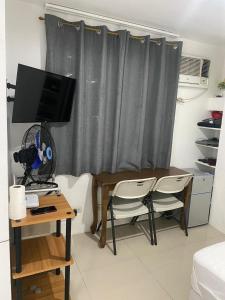 a living room with a table and a desk with a television at Cityscape Tower 2 Condo in Midtown Cebu in Cebu City +9 photos