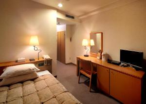 Habitación de hotel con cama y escritorio con ordenador en Kagoshima Sun Royal Hotel, en Kagoshima