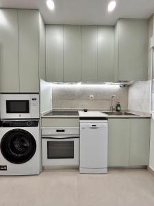 Una cocina con gabinetes blancos, fregadero y lavavajillas. en AeroSuites102 Alojamiento Madrid, en Madrid 6 fotos más