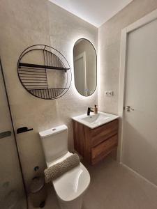 Un baño con inodoro, lavabo y espejo. en AeroSuites102 Alojamiento Madrid, en Madrid