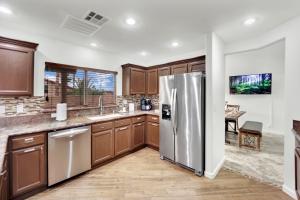 une cuisine avec des armoires en bois et un réfrigérateur en acier inoxydable dans l'établissement Heritage Haven Villa, à Las Vegas