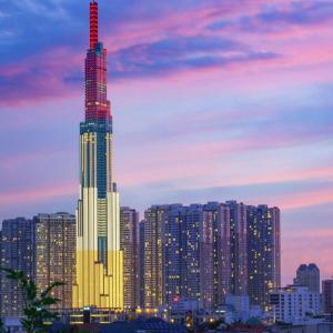 a city skyline with a tall building at dusk at Glorious CENTRAL Loft - Near BenThanh Market - Walk to METRO in Ho Chi Minh City