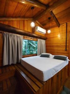 a bed in a wooden room with a window at Sítio em Nova Veneza - Caminho dos Pinheiros in Siderópolis