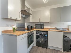 a kitchen with white cabinets and a washing machine at Cherry tree in Manchester +23 photos