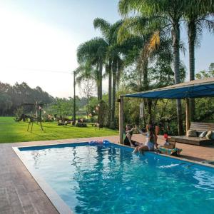 a group of people sitting on the edge of a swimming pool at Sítio em Nova Veneza - Caminho dos Pinheiros in Siderópolis