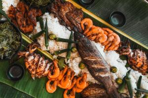 a plate of food with seafood on a banana leaf at Cabang Campsite - Private Island Experience in San Vicente