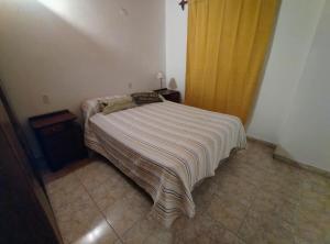 a small bedroom with a bed with a striped blanket at La Clavelina in Potrerillos