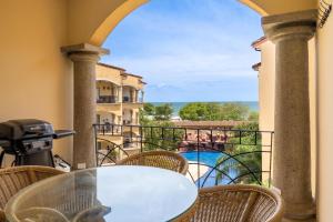 a table on a balcony with a view of a pool at Sunrise 27- 2 Bedroom Ocean View Condo in Tamarindo