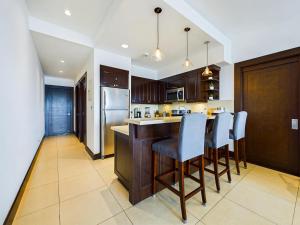 a kitchen with a bar with chairs and a refrigerator at 360 Splendor 302-Ocean View Condo-Breakfast in Playa Flamingo