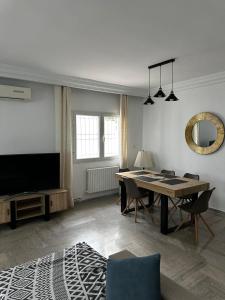 ein Wohnzimmer mit Tisch und Fernseher in der Unterkunft Green Hôte piscine sidi bou said in Dar Salah Bey