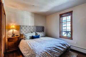 布雷肯里奇1 Bedroom Mountain Condo Located In Historic Downtown Breckenridge Near Shopping, Dining, And Restaurants的卧室里有一张床，床铺是蓝色的，还有一扇窗户