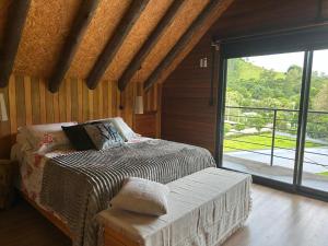 a bedroom with a bed and a sliding glass door at Vale do Vento Garden in Farroupilha
