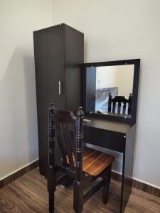 a black desk with a mirror and a wooden chair at Sri Adhinath Homes in Kanchipuram