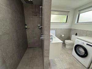 a bathroom with a shower and a washing machine at Rural Studio in Hastings +7 photos