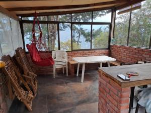 eine Terrasse mit einem Tisch, Stühlen und einer Hängematte in der Unterkunft Acogedora Cabaña Vacacional en los Yungas in Chirca + 2 Fotos