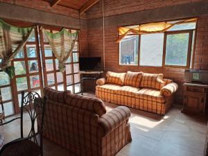 ein Wohnzimmer mit zwei Sofas und einem Fernseher in der Unterkunft Acogedora Cabaña Vacacional en los Yungas in Chirca