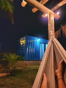 a person sitting in a hammock in front of a blue building at POUSADAGiraGarden Containers in Arroio do Silva