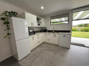 a kitchen with white appliances and a large window at Rural Studio in Hastings