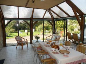 a dining room with a table and chairs and windows at Gîte La Maison d'Amélie in La Chapelle-Saint-Aubert