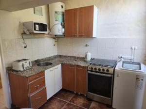 Una pequeña cocina con estufa y fregadero. en Beautiful Casa Madrynense, en Puerto Madryn 6 fotos más