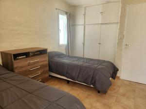 Un dormitorio con dos camas y una cómoda y un armario. en Beautiful Casa Madrynense, en Puerto Madryn